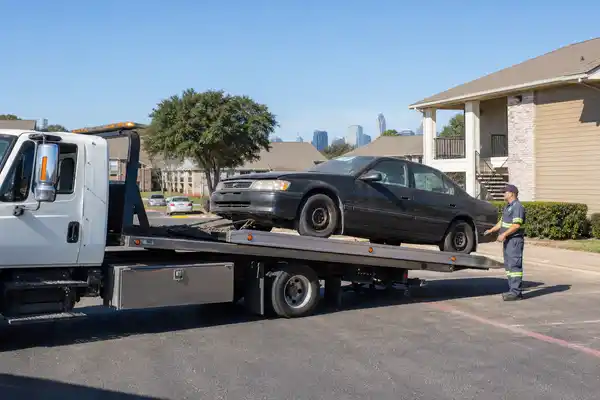 Flatbed tow truck removing unauthorized vehicle from Dallas apartment complex parking lot
